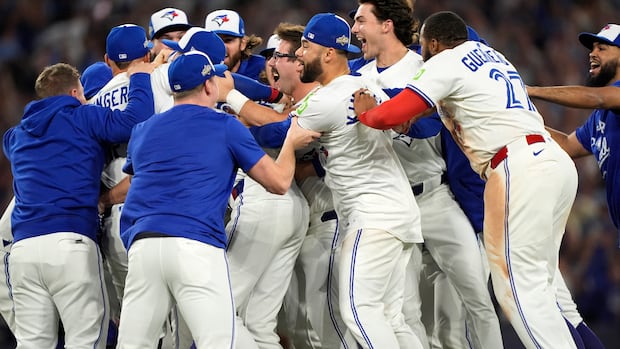 A group of baseball players group hug in a stadium