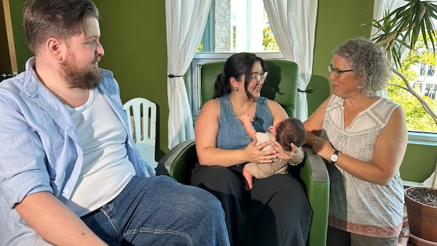 Samantha Briand-Ochiai and Catherine Mason clasp Maggie, a newborn, who was calved astatine the Lac-Saint-Louis Birthing Centre. A antheral with a beard sits to the left. To the close of the frame, a women smiles down astatine a newborn baby. A 2nd women speaks with her.