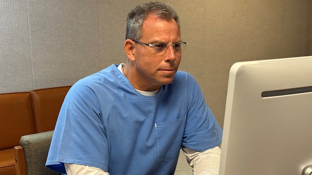 Man in blue shirt stares at computer screen