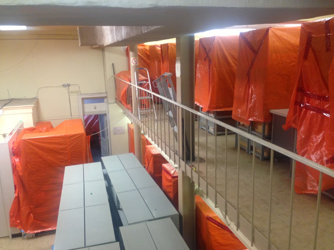 Orange tarps cover bookshelves inside the room of a building