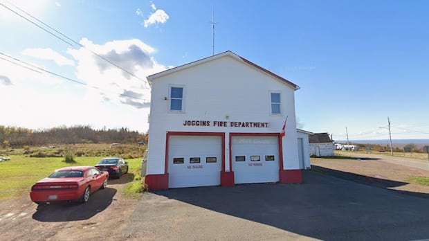 The Municipality of Cumberland says the Joggins volunteer fire department is no longer registered with the county. A fire hall. Two garage doors with red trim can be seen on the building. Both have three windows and a No Parking sign underneath.