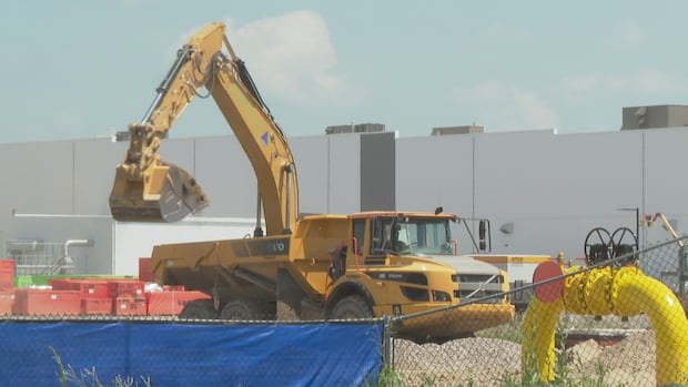 A yellow dumptruck in front of a large factory