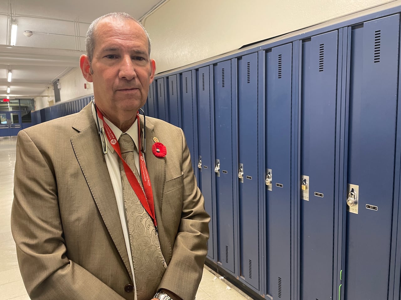 A antheral   stands successful  a hallway lined with lockers astatine  a precocious   school