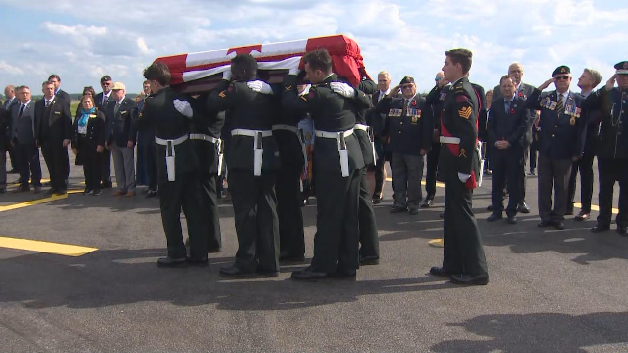 Several soldiers are carrying a casket on a airport runway.