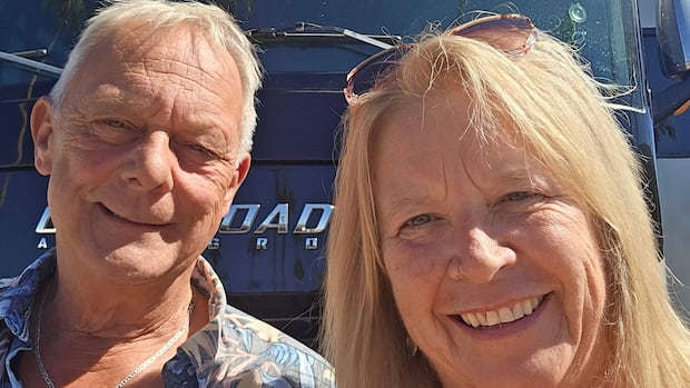 A couple standing in front of their motorhome. 