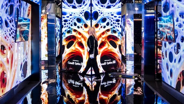 People walk through a display booth for the Mila, Quebec Artificial Intelligence Institute, at the All In AI conference in Montreal on Thursday, Sept., 25, 2025. A display booth showing off an AI research institute