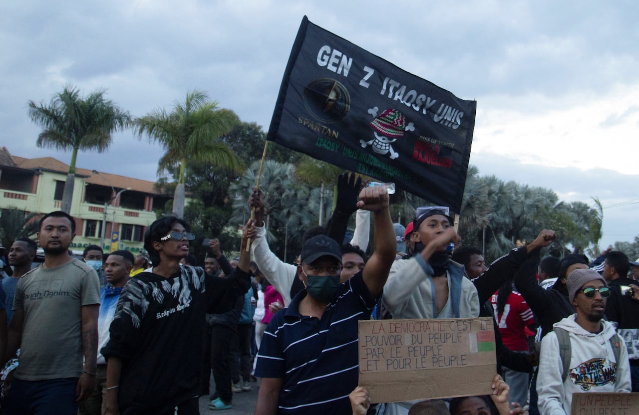 Young protesters wave a black flag with writing on it "Gen Z Itaosy Unis."