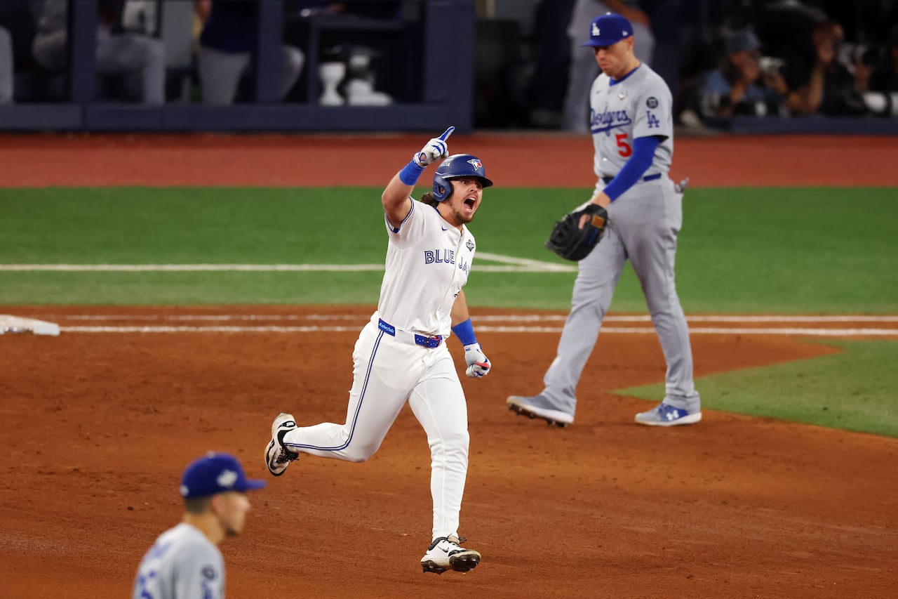Addison Barger #47 of the Toronto Blue Jays rounds the bases during the 2025 World Series with Dodgers player in background.