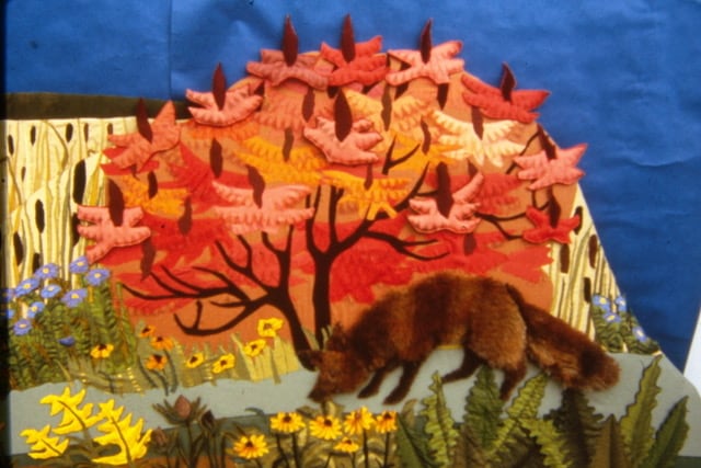 A colourful fabric mural of a fox on a garden path.