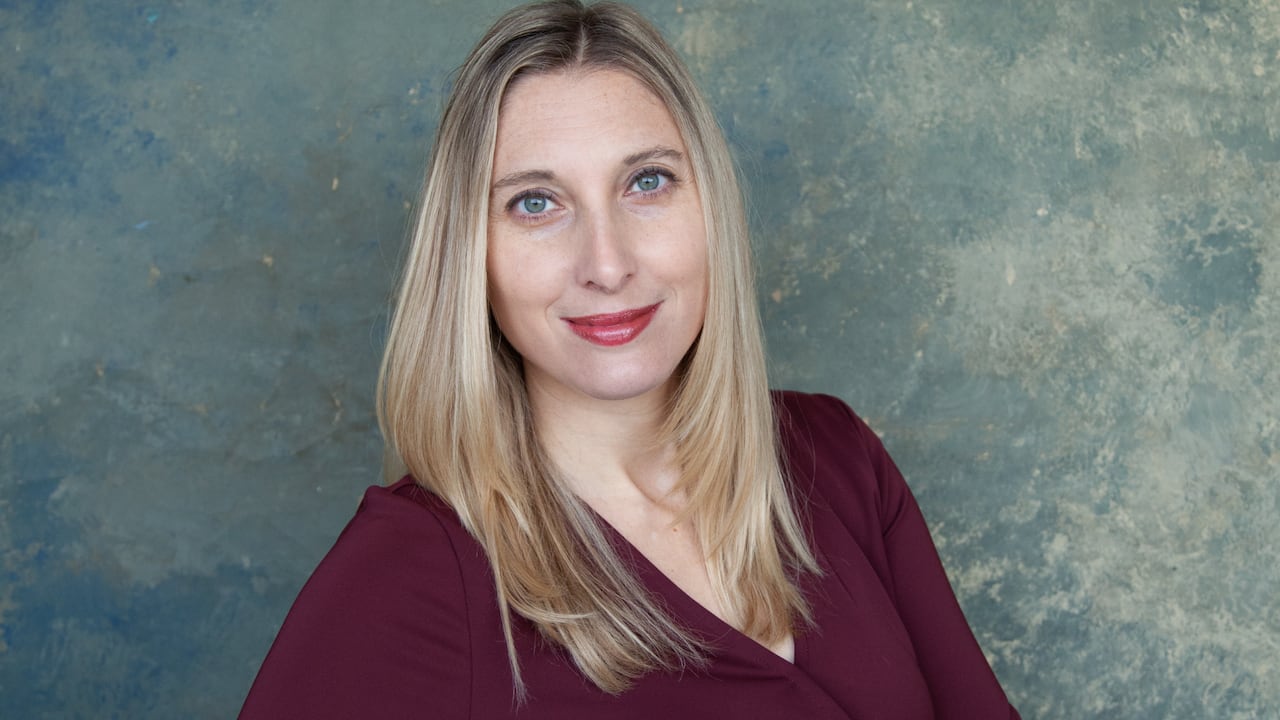 A woman with blonde hair smiles at the camera. 