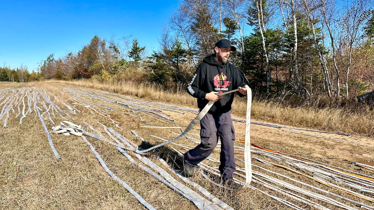 A man walks between rows of white hose line in a field.