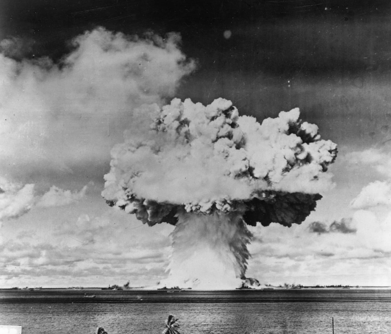 A black and white photo of a mushroom cloud over the ocean