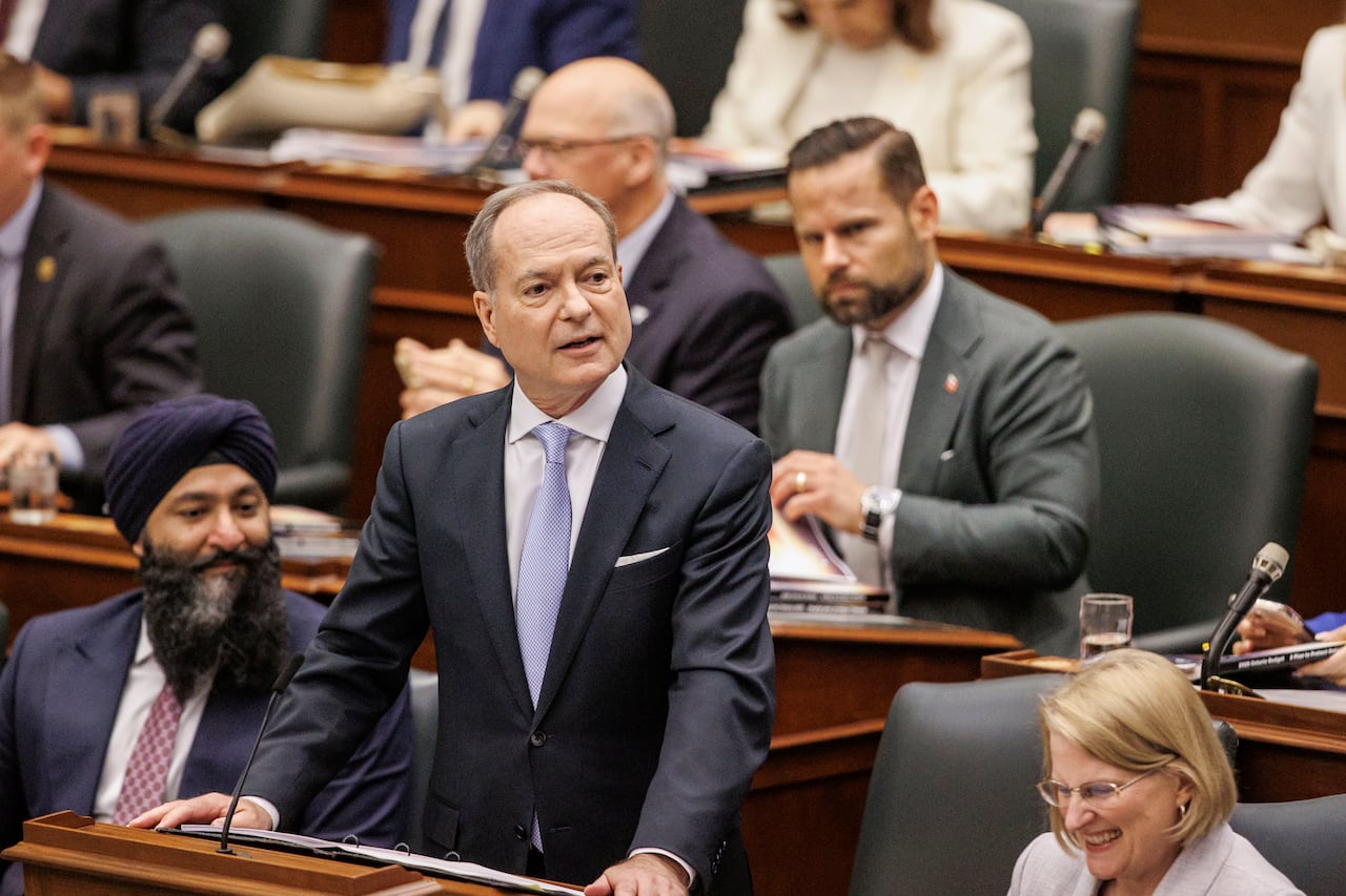 Mężczyzna stoi z rękami na biurku i przemawia do publiczności.