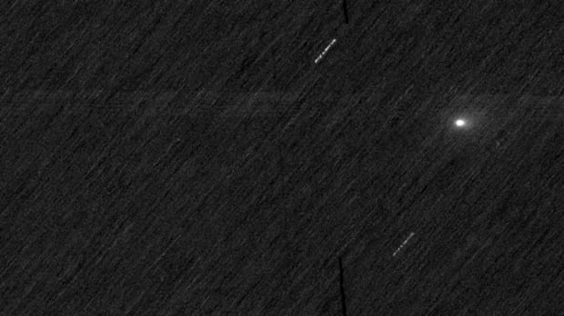 A photo taken from the European Space Agency's ExoMars Trace Gas Orbiter (TGO) spacecraft shows comet 3I/Atlas, revealing the coma of gas and dust surrounding the icy-rocky nucleus. A black space background with white streaks and a single fuzzy white dot. The streaks are stars and the dot is comet 3I/ATLAS.
