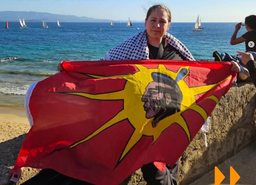 An Indigenous woman holds a red and yellow flag.