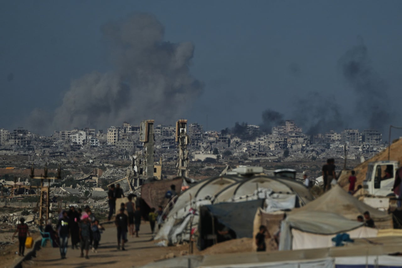 Smoke rises into the dark sky above buildings and tents