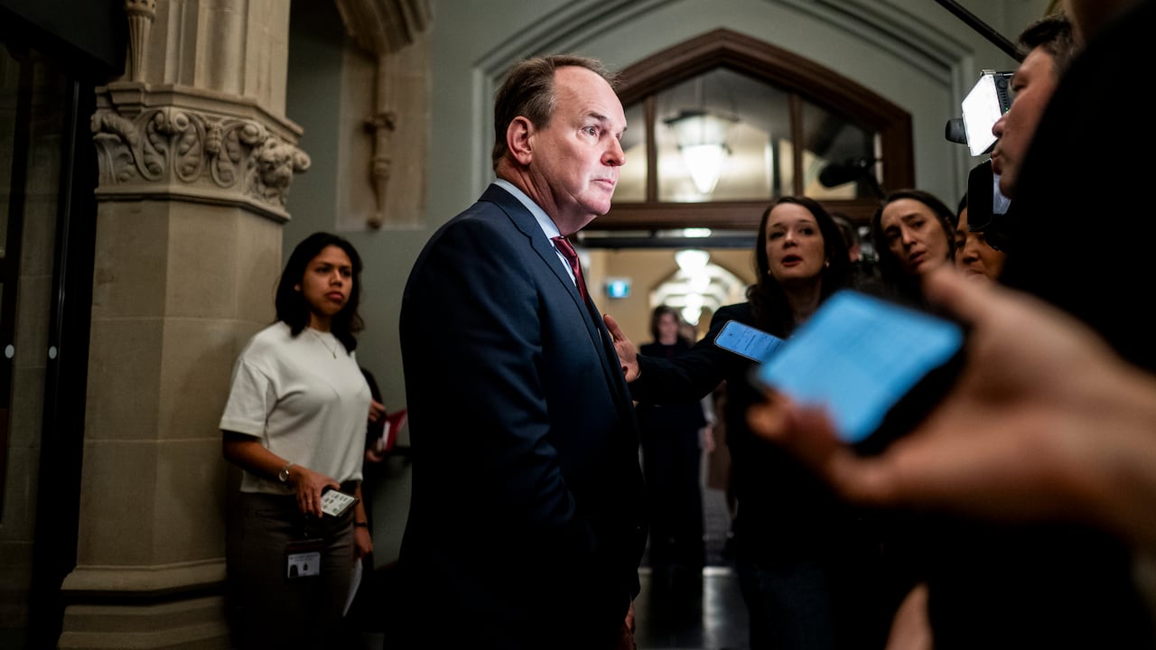 A man in a suit speaks to reporters gathered in the corridors of the House of Commons.