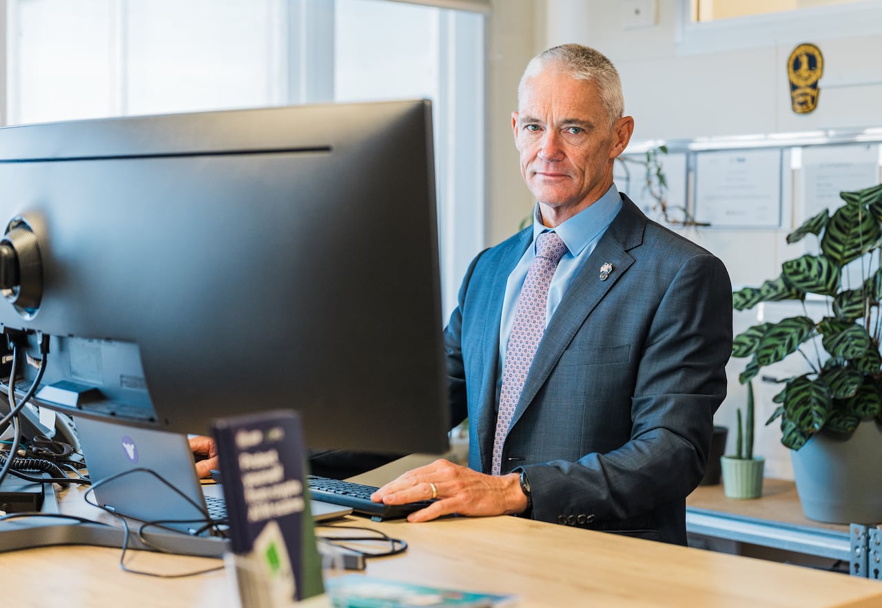 Man standing behind a desk with a computer on it.
