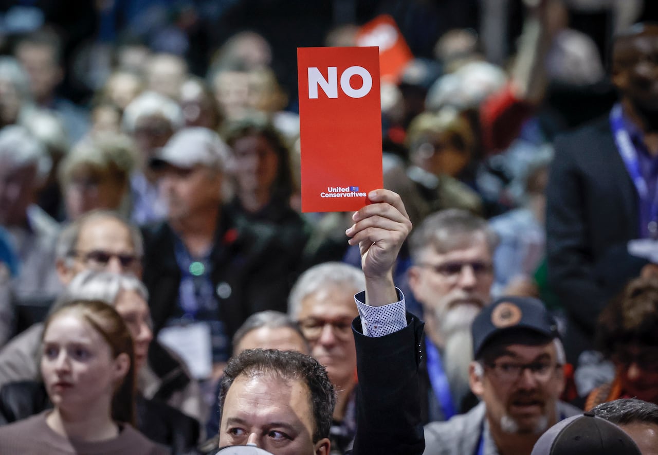 Man holds a No vote placard while almost nobody does so behind him.