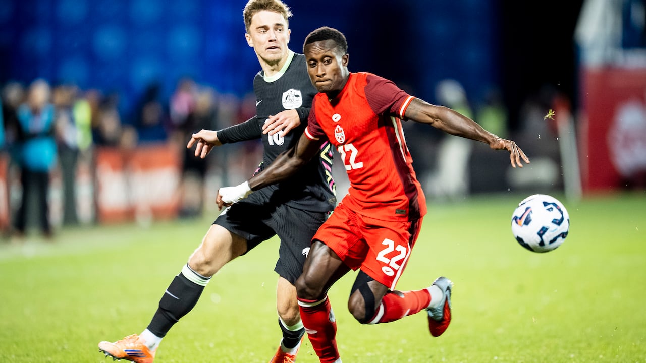 Two male soccer players battle for the ball.