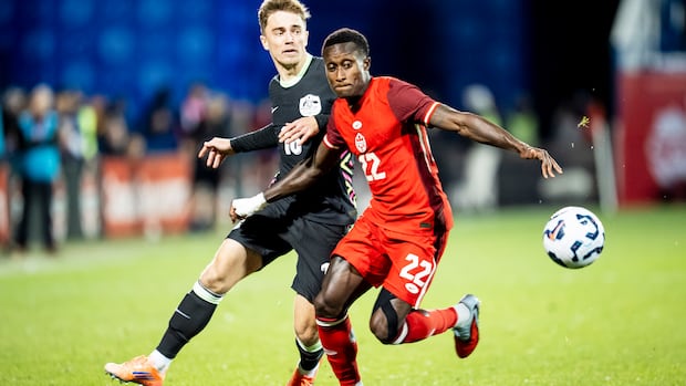Two male soccer players battle for the ball.