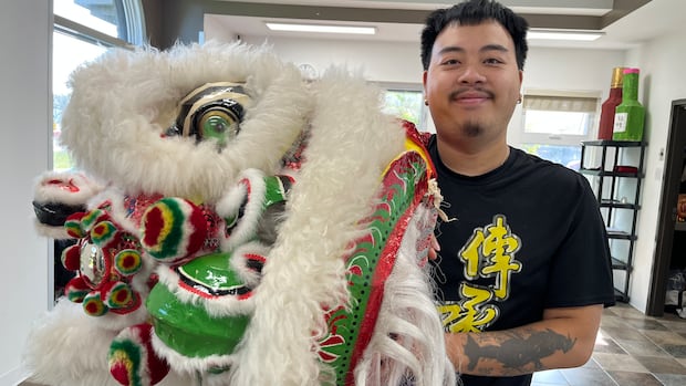 A man holds up a costume used in a traditional Chinese lion dance