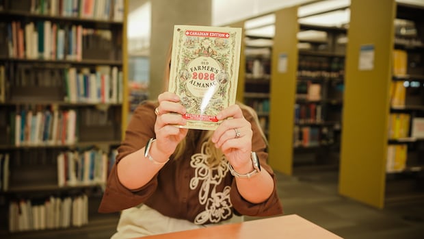 CBC's Johanna Wagstaffe holds a copy of The Old Farmer's Almanac in the Vancouver Public Library.
