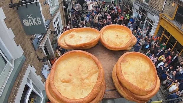 Stacks of Yorkshire puddings sit atop a plinth above a crowd.