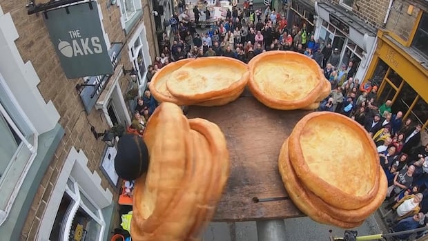 Stacks of Yorkshire puddings sit atop a plinth above a crowd.