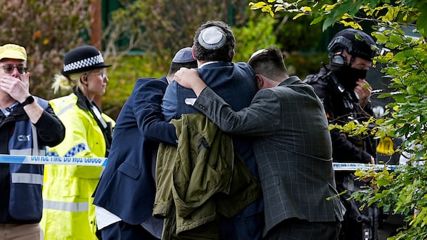 Men huddled in an embrace before police caution tape