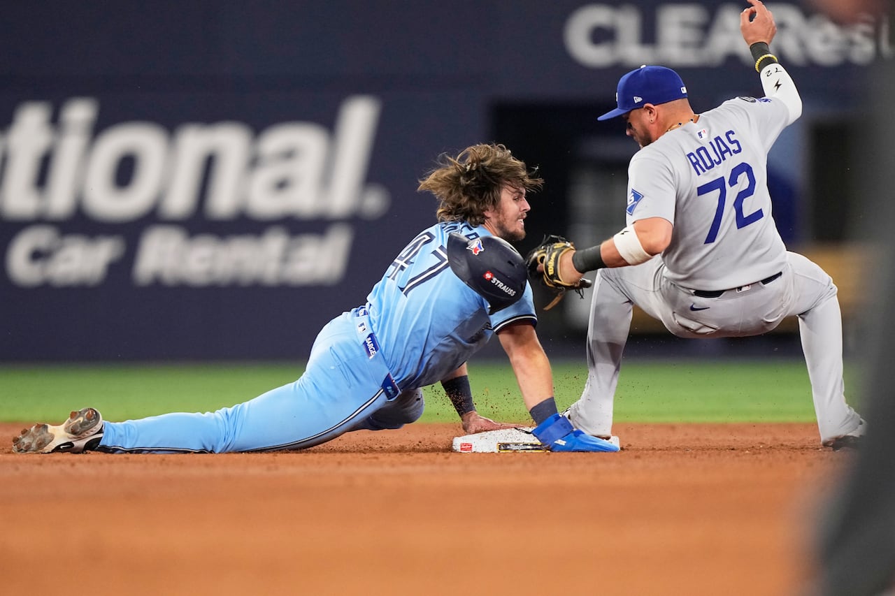 Blue Jays Addison Barger dives into second base as Dodgers' Miguel Rojas fields the ball with his foot on the bag at Rogers Centre