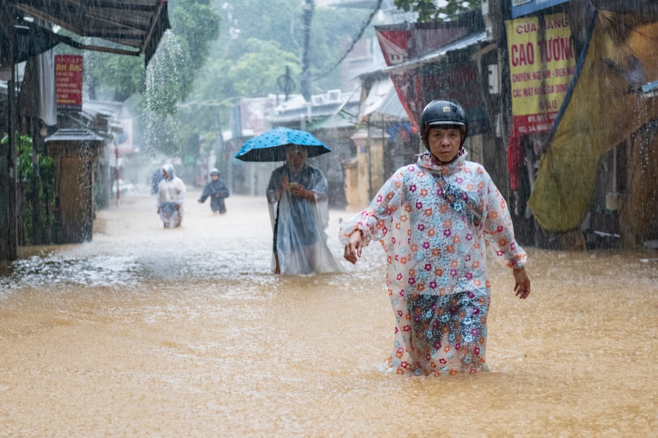 Two women are shown walking successful  azygous  record  with h2o  up   to their knees arsenic  rainfall  pours down   connected  a metropolis  street.