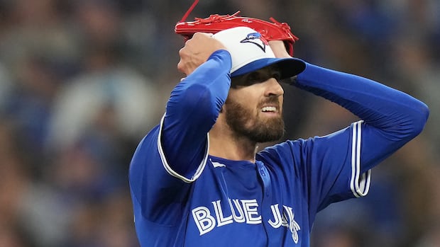 A man in a blue uniform and ball cap reacts with disbelief.