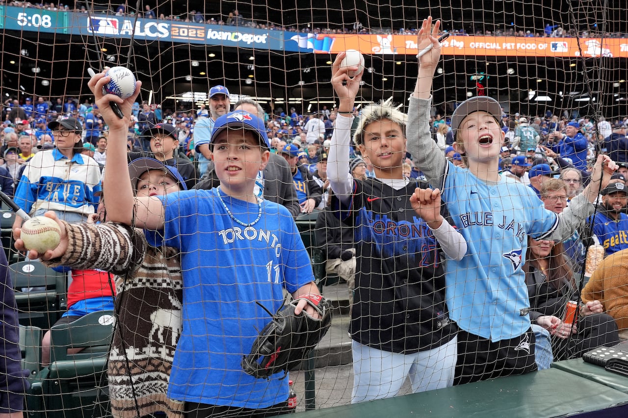 Young boys at a Blue Jays game holding up baseballs