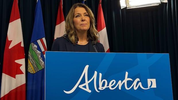 Alberta Premier Danielle Smith speaks to reporters on Oct. 23, 2025. A person standing behind a desk.