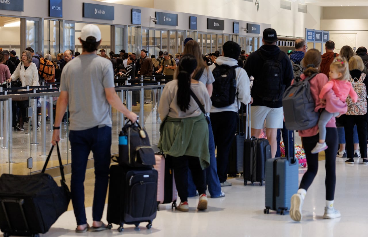 Travelers wait to clear security at a busy airport.