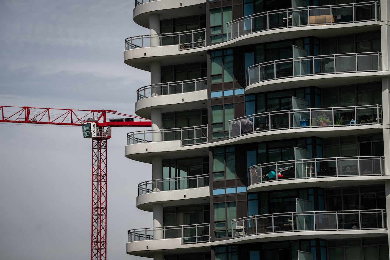 A red crane beside a condo tower. 