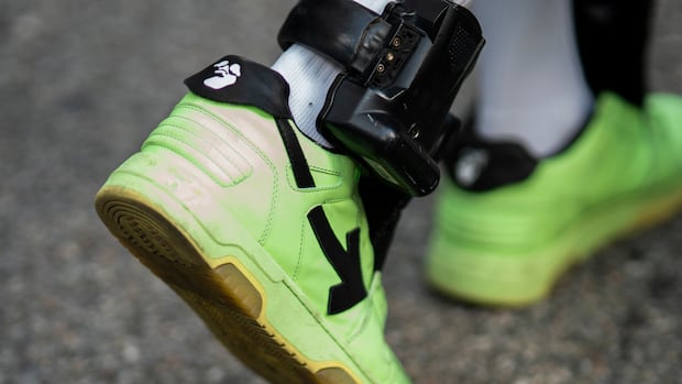 Former NBA basketball player Sebastian Telfair wears an ankle monitor as he departs departs Manhattan Federal Court, Thursday, Oct. 7, 2021, in New York. Federal authorities say 18 former NBA players, including Telfair, have been charged with allegedly pocketing $2.5 million illegally by defrauding the league's health and welfare benefit plan. A closeup shows a person wearing bright green shoes and an ankle monitor device.