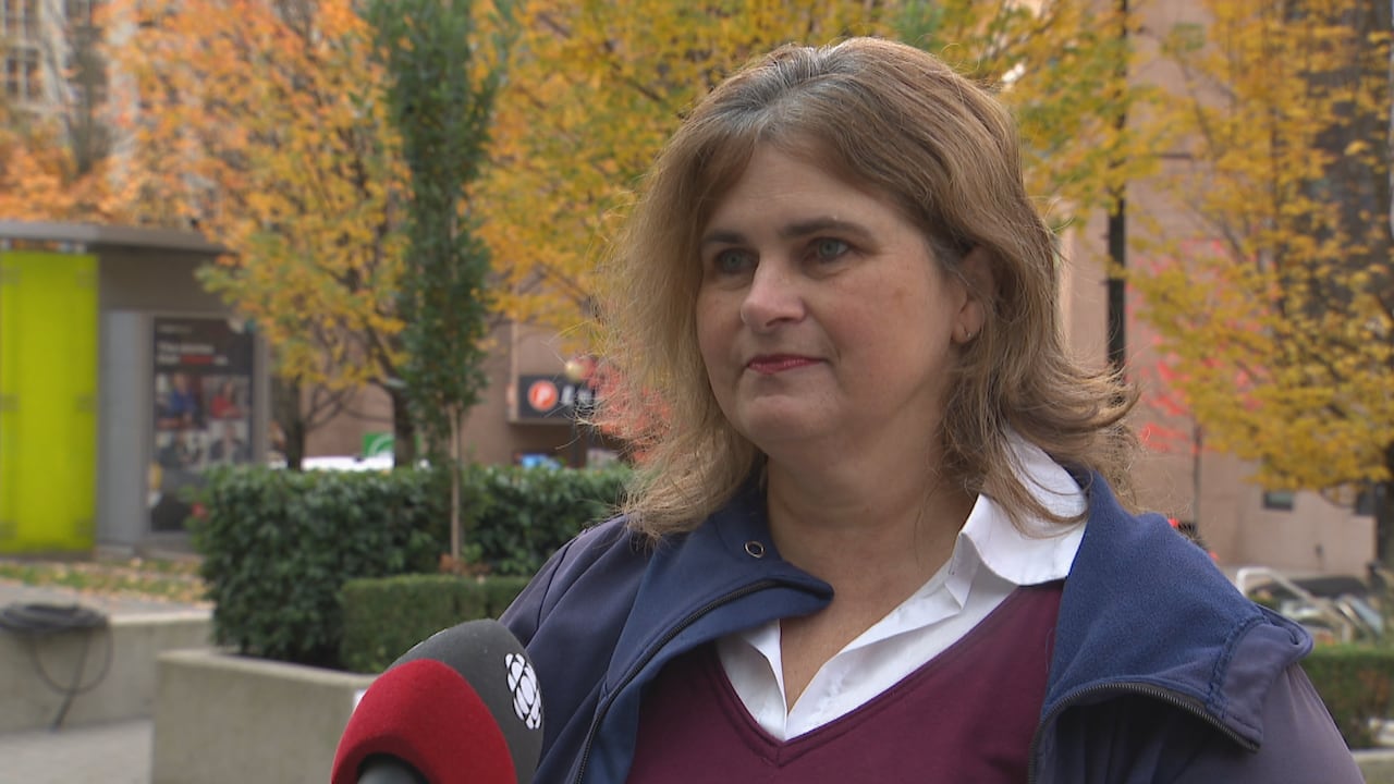 A pistillate with airy brownish hair, wearing a maroon apical and bluish jacket, stands extracurricular among autumn trees portion speaking into a CBC-branded microphone successful downtown Vancouver.