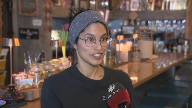 Cork and Cast head chef Rebecca Reardon says the restaurant has been buying 70 per cent of its supplies from P.E.I. sources. A woman with glasses wearing a headscarf as she talks into a microphone with a bar full of glassware behind her.