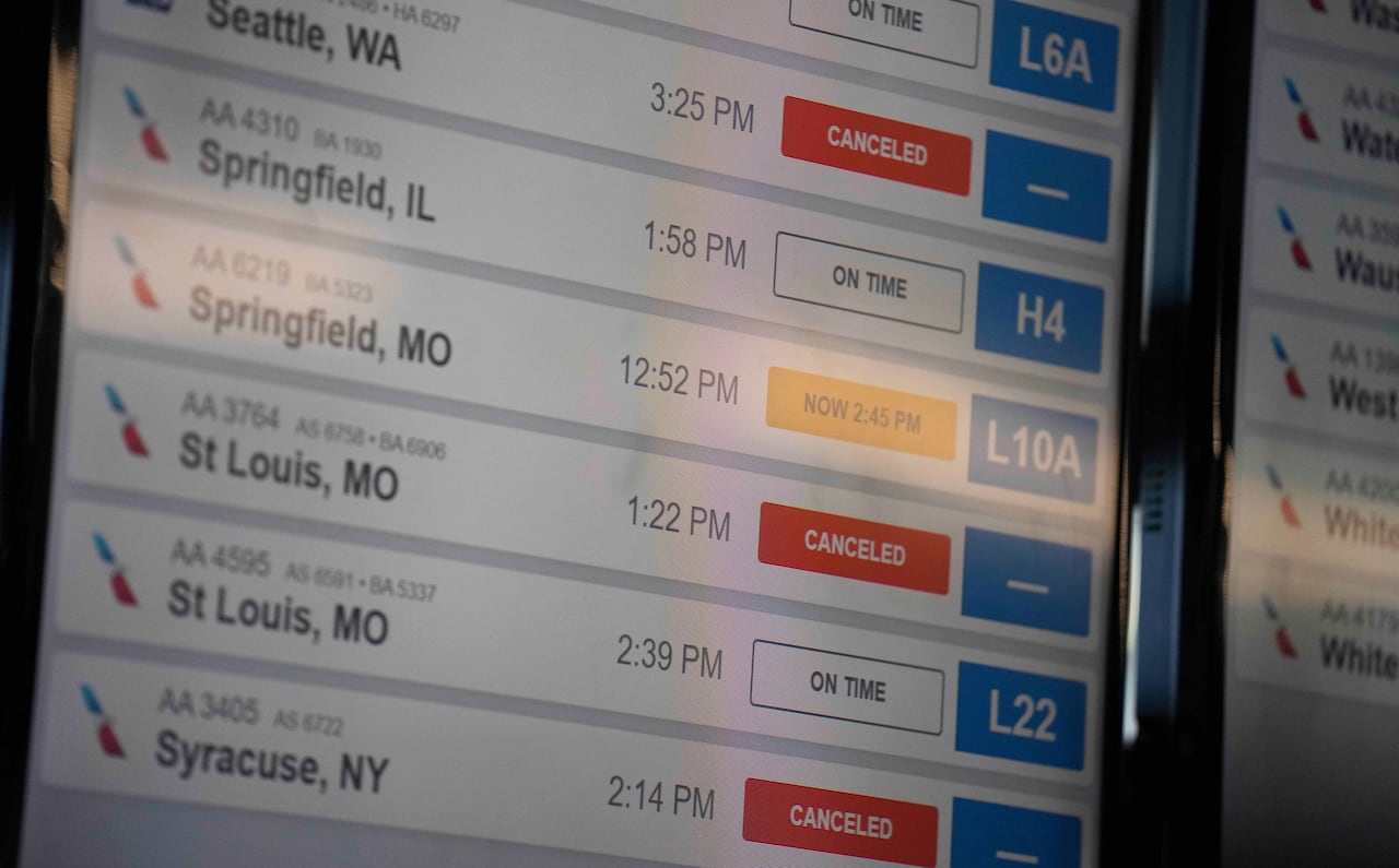 An airport display shows flights to Seattle, St. Louis, and Syracuse marked as cancelled. 
