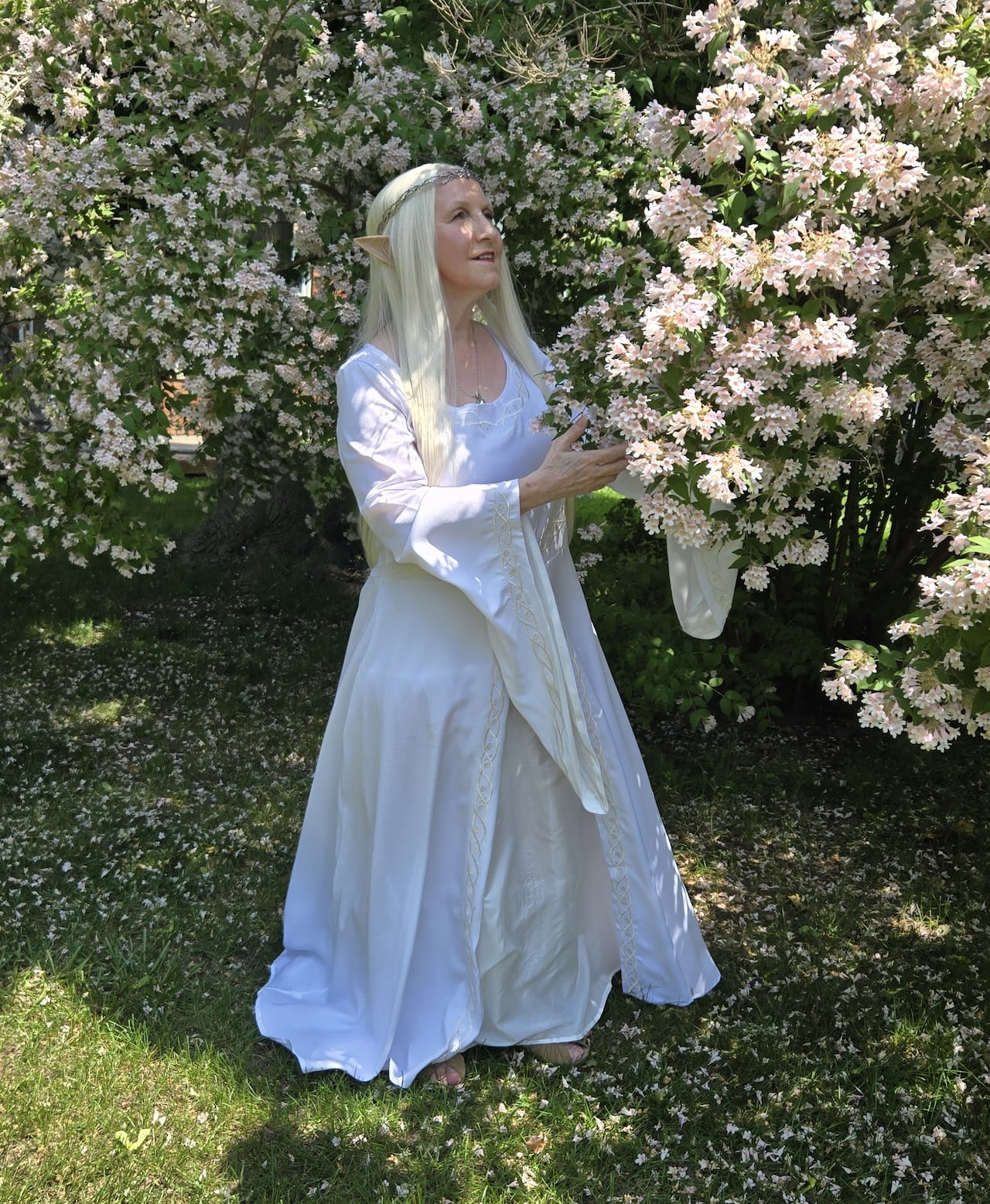 A woman is dressed in a white dress with a long blonde wig and pointed ears.
