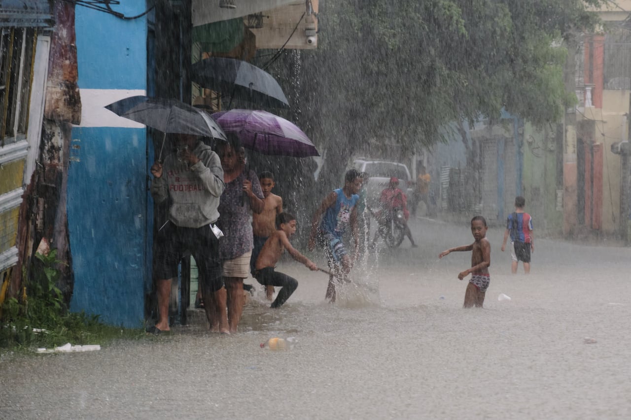 Children play in the flooded road in the rain.