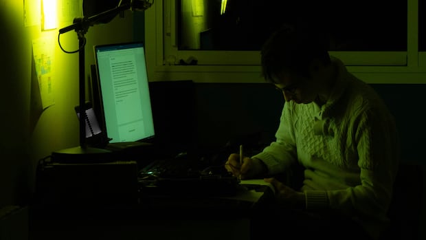 A person works at a computer in the dark. A person works at a computer in the dark.