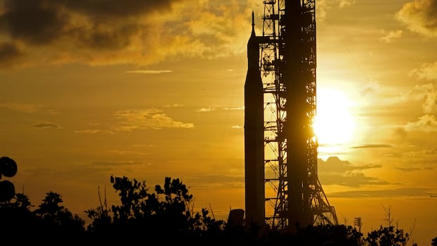 A rocket in shadow, with a sun setting in the background.