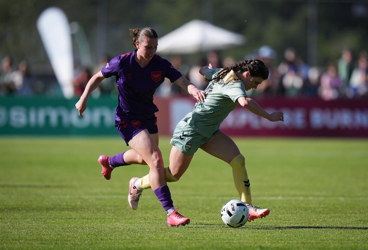 Two women compete for the ball during a soccer game.