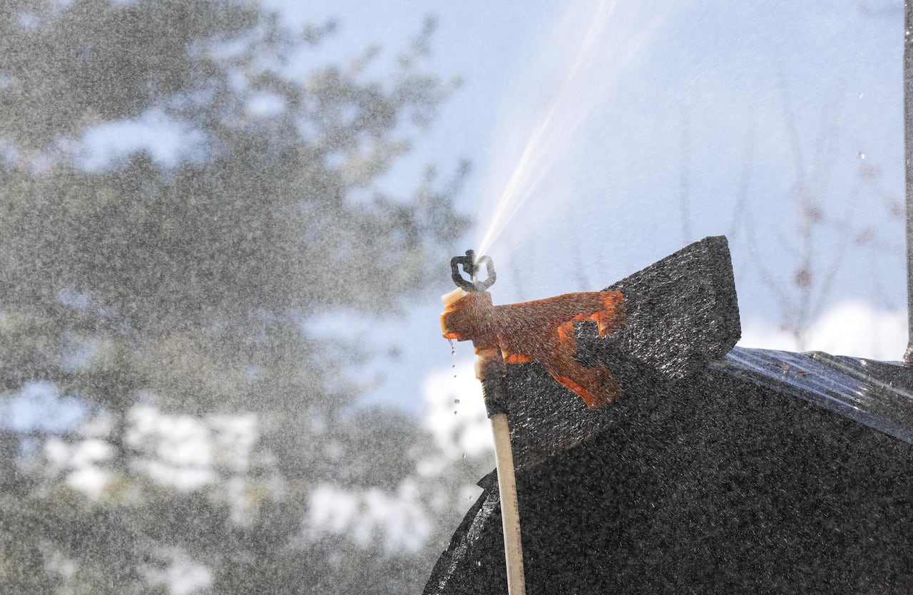 A sprinklers spraying water from the peak of a home.
