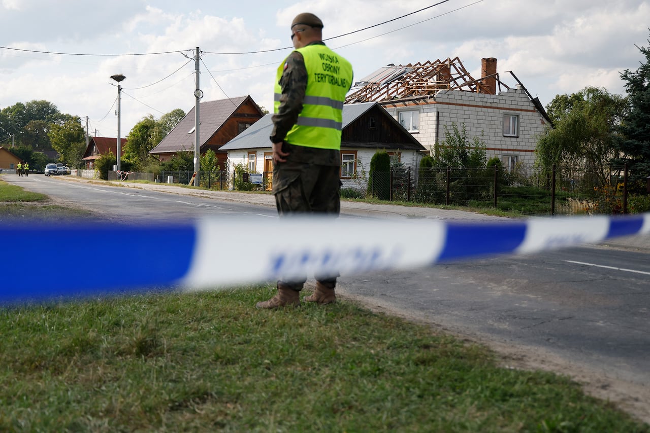 Officers are standing in the street near the damaged house.