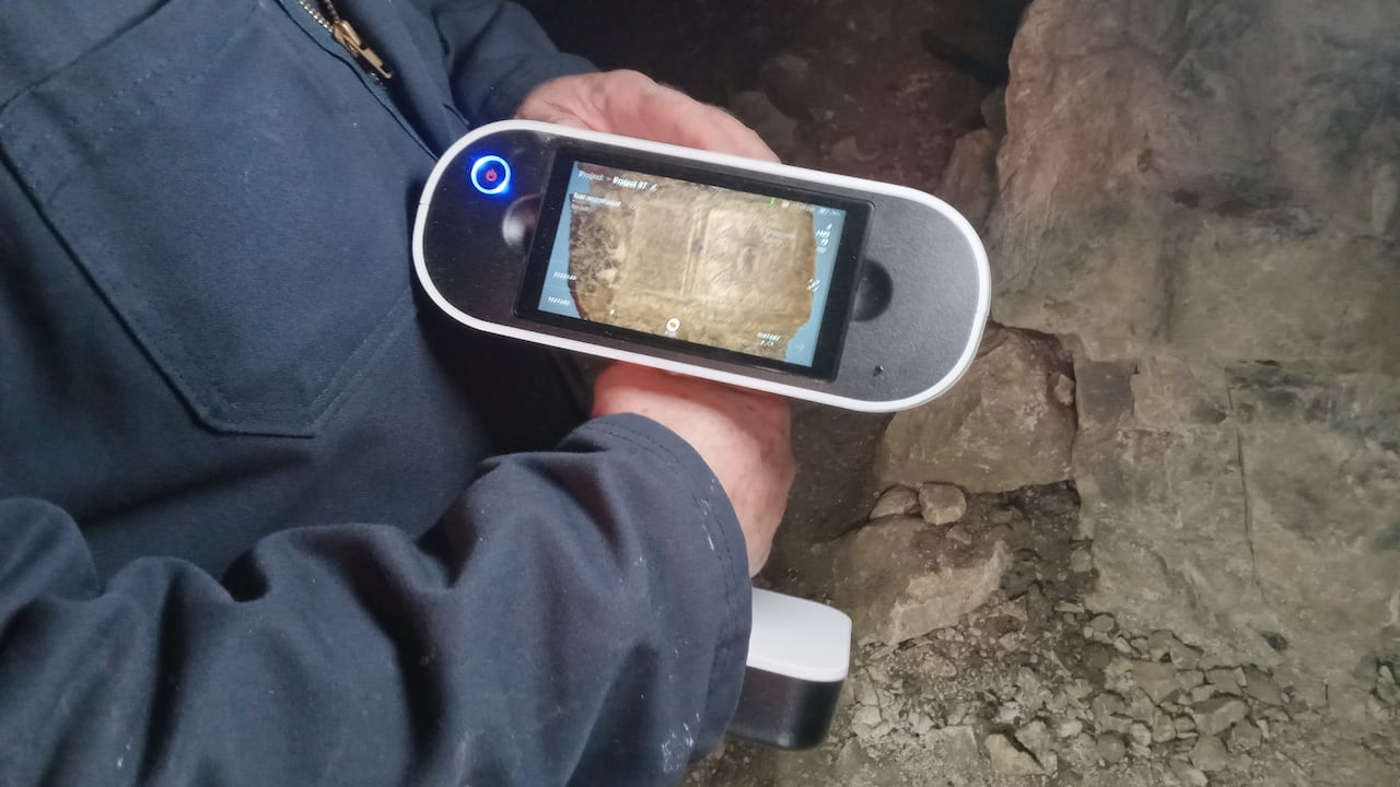 A hand holding a device with a screen.