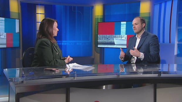 CBC News: Compass host Louise Martin speaks with federal Housing Minister Nathaniel Erskine-Smith. A man and a woman talk to each other as they sit at a TV news desk.